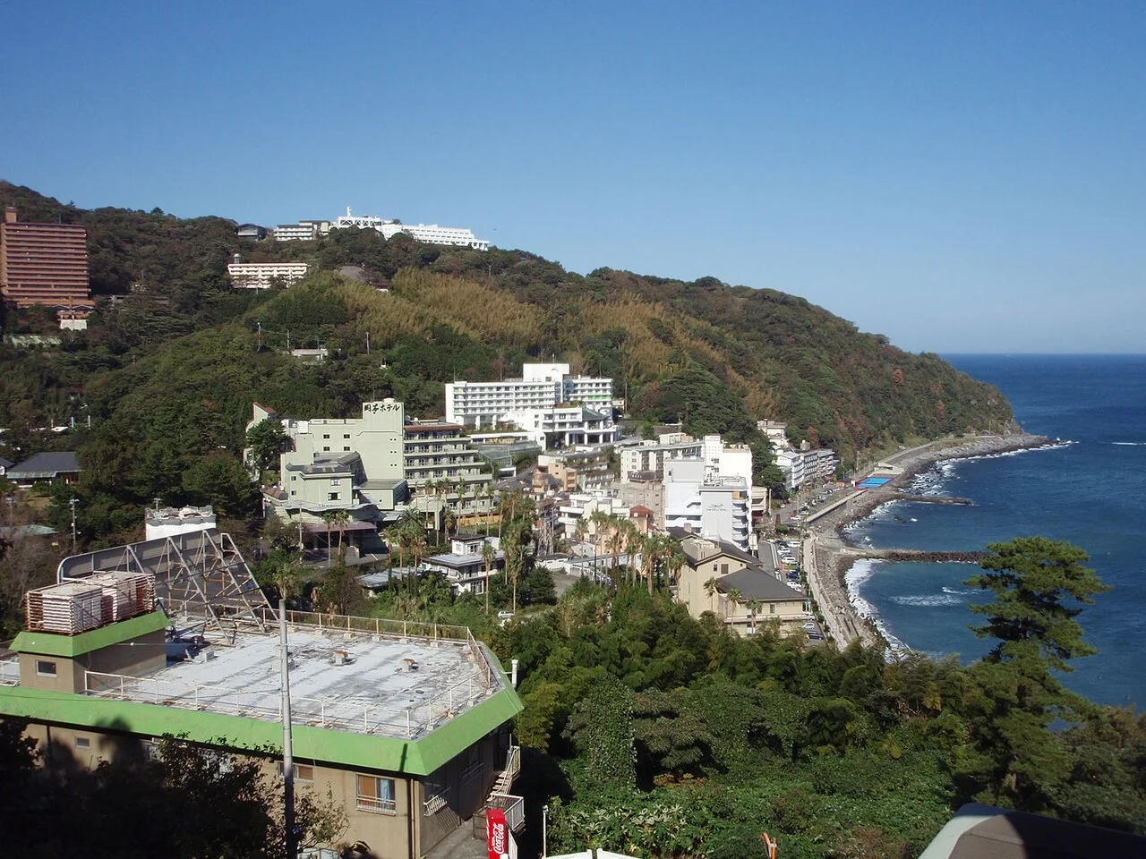 Atagawa hotels and shoreline below wooded coastal hills