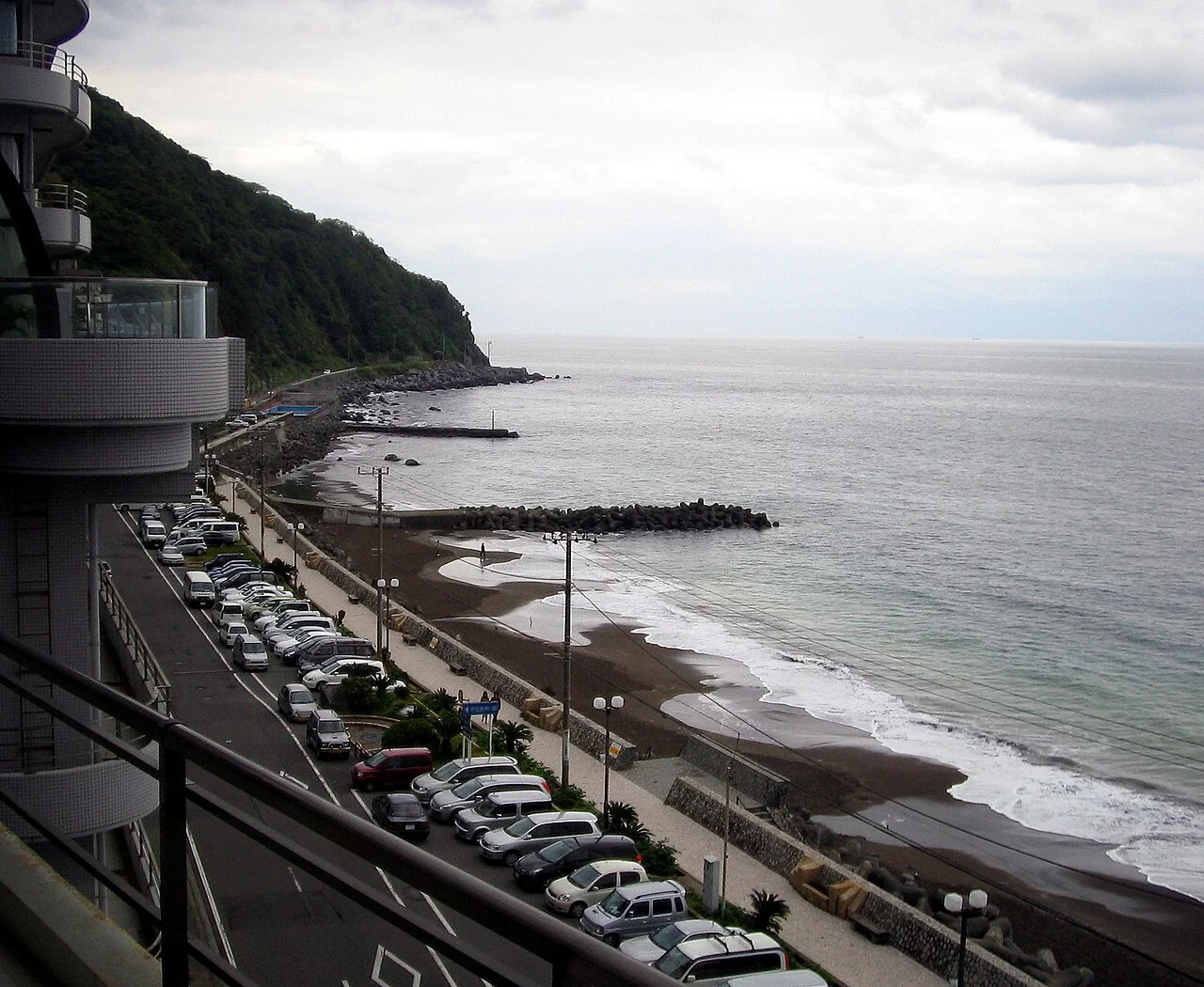 Atagawa sandy shore, breakwaters and coastal hotels beneath a cloudy sky
