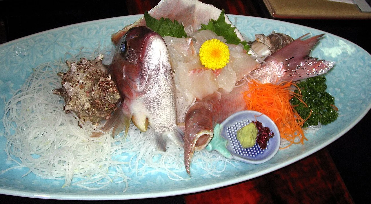 Plate of sashimi with shredded daikon and flower garnish in Atagawa
